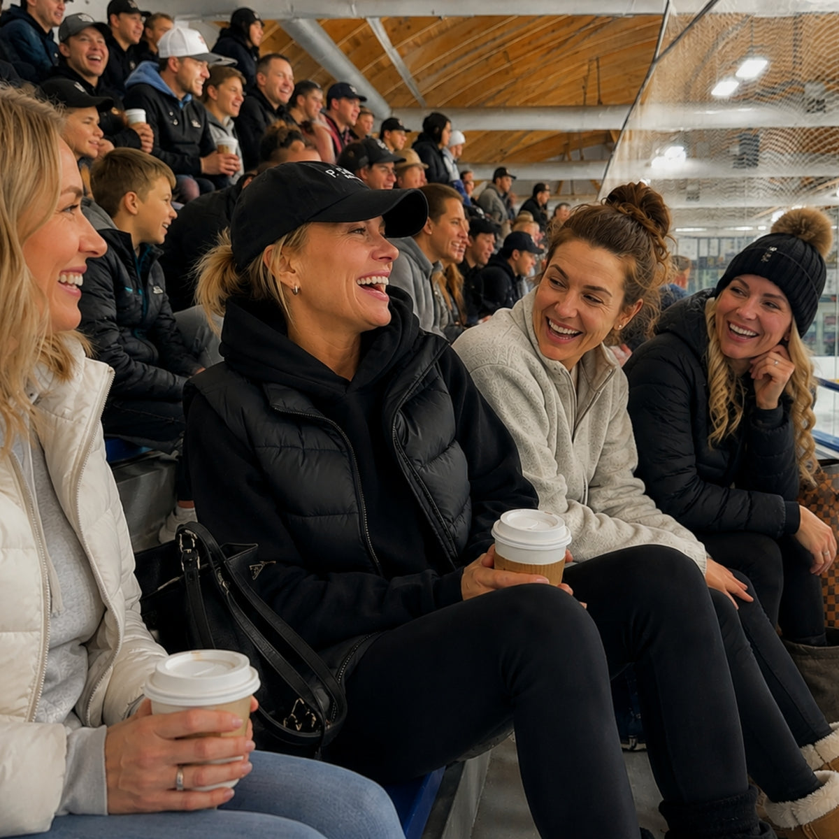 Hockey moms staying warm while watching a game at a cold ice rink