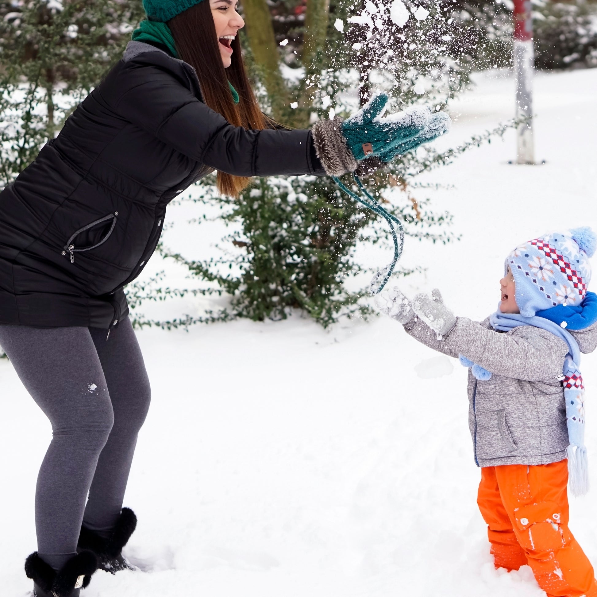 Mom and child playing together in the snow on a cold winter day