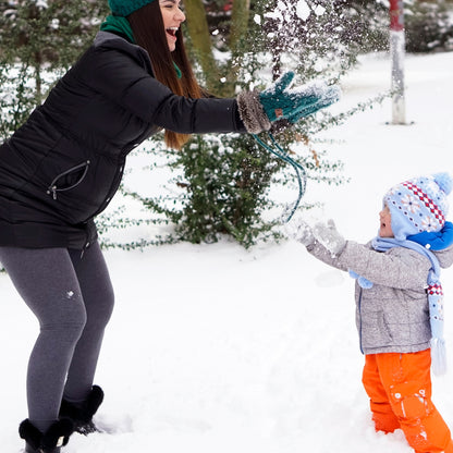 Mom and child playing together in the snow on a cold winter day